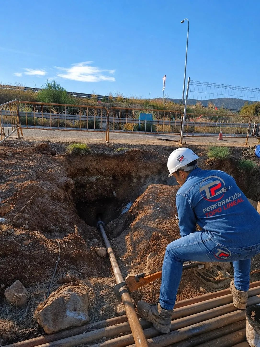 Operario de Perforación Topo Lineal supervisando la entrada de la perforación junto a una autopista