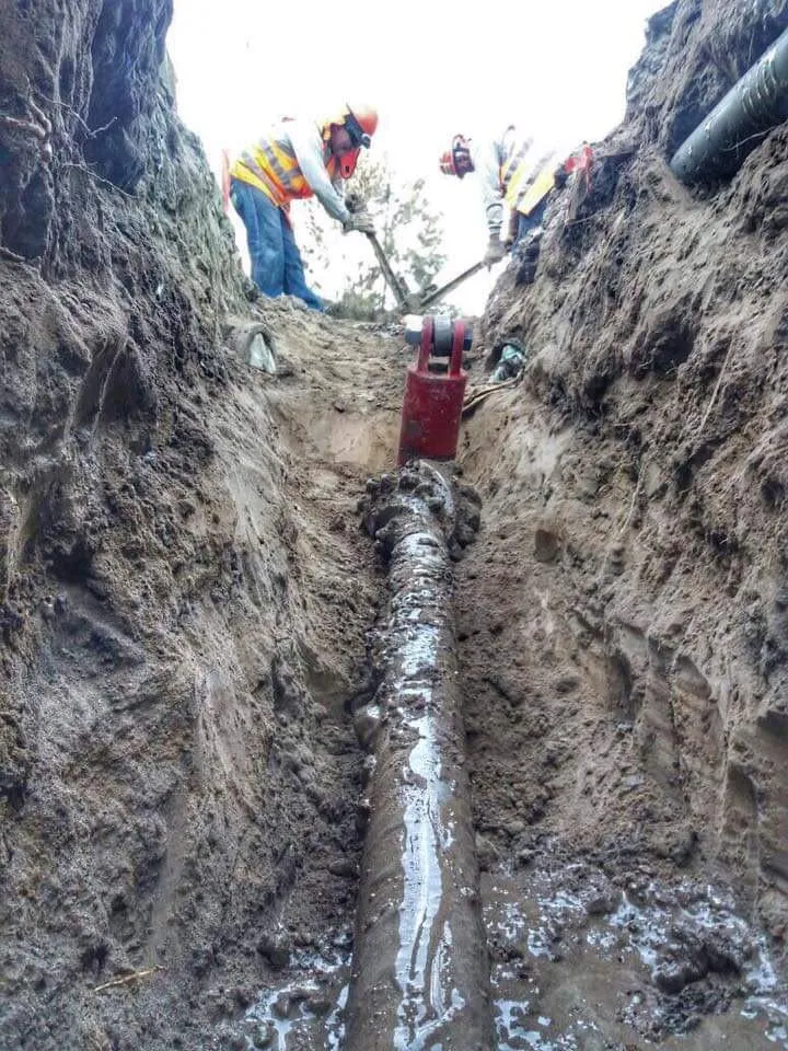 Cabezal de perforación y tubería instalada bajo tierra vista desde la zanja de salida