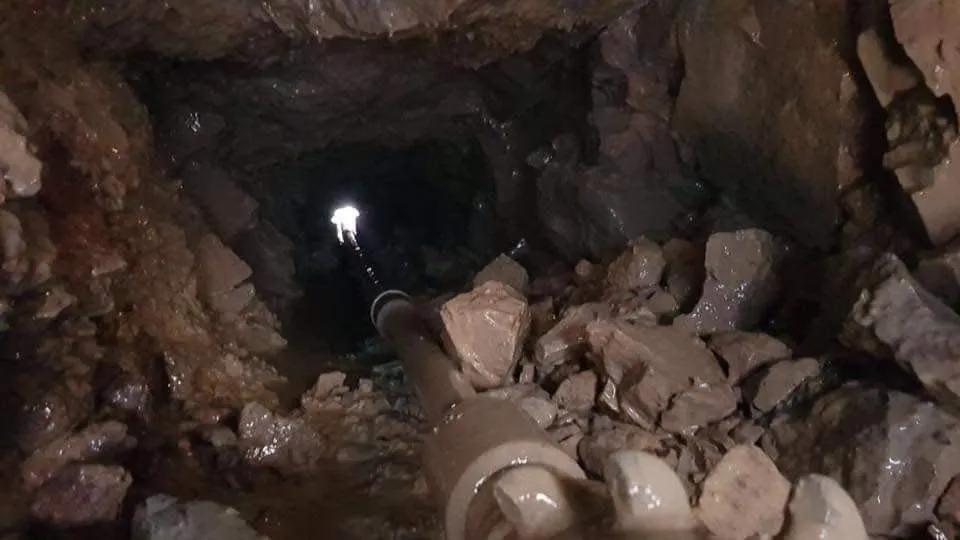 Varillaje de perforación avanzando por un túnel excavado en roca hasta la boca de salida